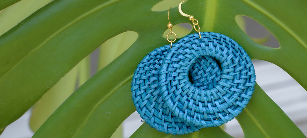 Hand woven rattan earrings from Mactan Island Philippines displayed on philodendron leaf.