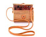 Natural rattan handbag hand woven in Bali Indonesia with leather strap and brass clasp, showing colorful, patterned cotton lining.