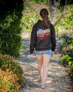 Heavyweight black hoodie hand printed in Philippines with Hollywood Sign motif printed on back in red, white & blue, shown on  female model.