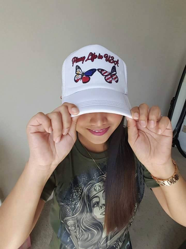 Pinay Life in USA logo cap in all white, showing group logo along with two butterflies in Philippines & American flag colors on front white panel, displayed on female model.