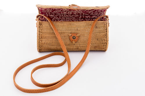 Natural rattan handbag with oval shape hand woven in Bali Indonesia with leather strap & brass clasp, showing colorful cotton lining.