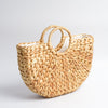 Roomy tote bag handmade in Bali from water hyacinth leaves, pictured to show sturdy overlapping weave with flat bottom and rounded sides. Sturdy round handles are woven directly into body. Light tan in color. Pictured to show white cotton lining.