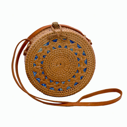 Round, natural rattan handbag hand woven in Bali showing tight rattan weaving, braided design, leather strap, & braided ribbon clasp.