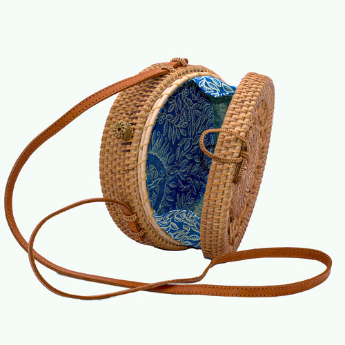 Natural rattan handbag hand woven in Bali Indonesia with leather strap & brass clasp, showing detail of colorful, patterned cotton lining.