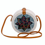 Round white rattan handbag hand woven in Bali Indonesia with hand painted insert in red, black, yellow & green, leather strap & brass clasp.
