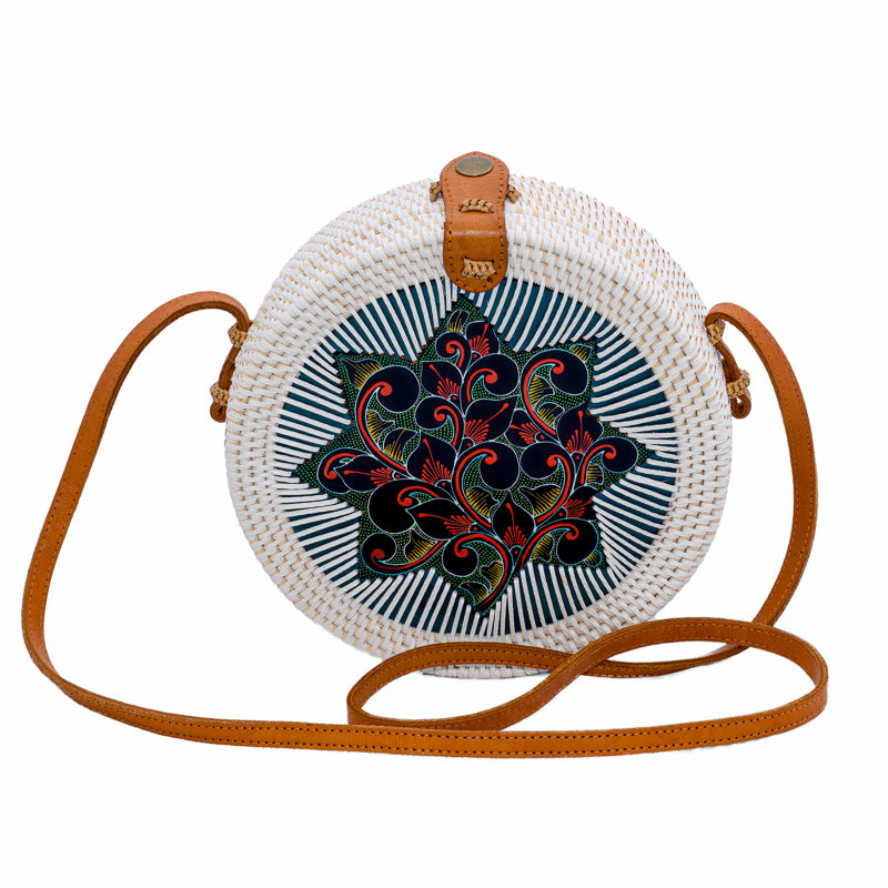 Round white rattan handbag hand woven in Bali Indonesia with hand painted insert in red, black, yellow & green, leather strap & brass clasp.