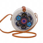 Round white rattan handbag hand woven in Bali with hand painted insert in purple, blue, red & black in a star-shaped design, along with leather strap & brass clasp.