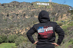 Heavyweight black hoodie hand printed in Philippines with Hollywood sign motif on female model with the Holloywoood sign in background.